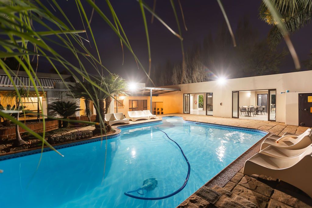 Swimming pool lit up at night beside the covered patio